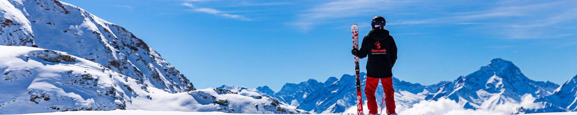 A Sunweb guide with cool branded Sunweb skis in front of a mountain