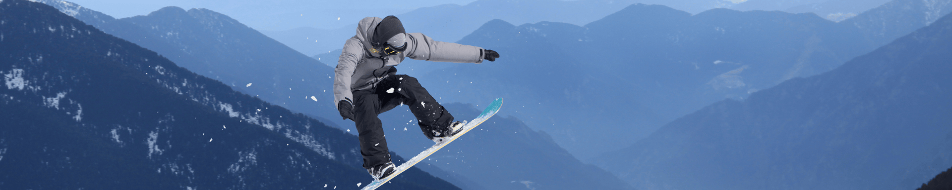 snowboarder jumps in the sky with mountains on the background